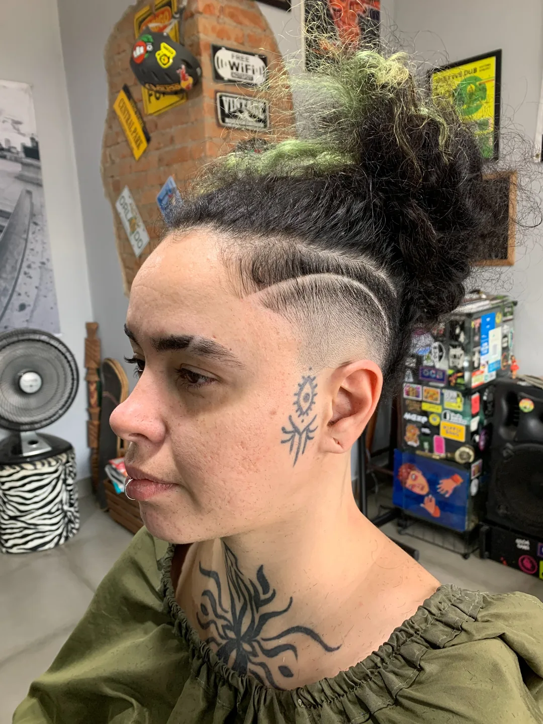 Corte com desenho nas laterais e cabelo preso no topo