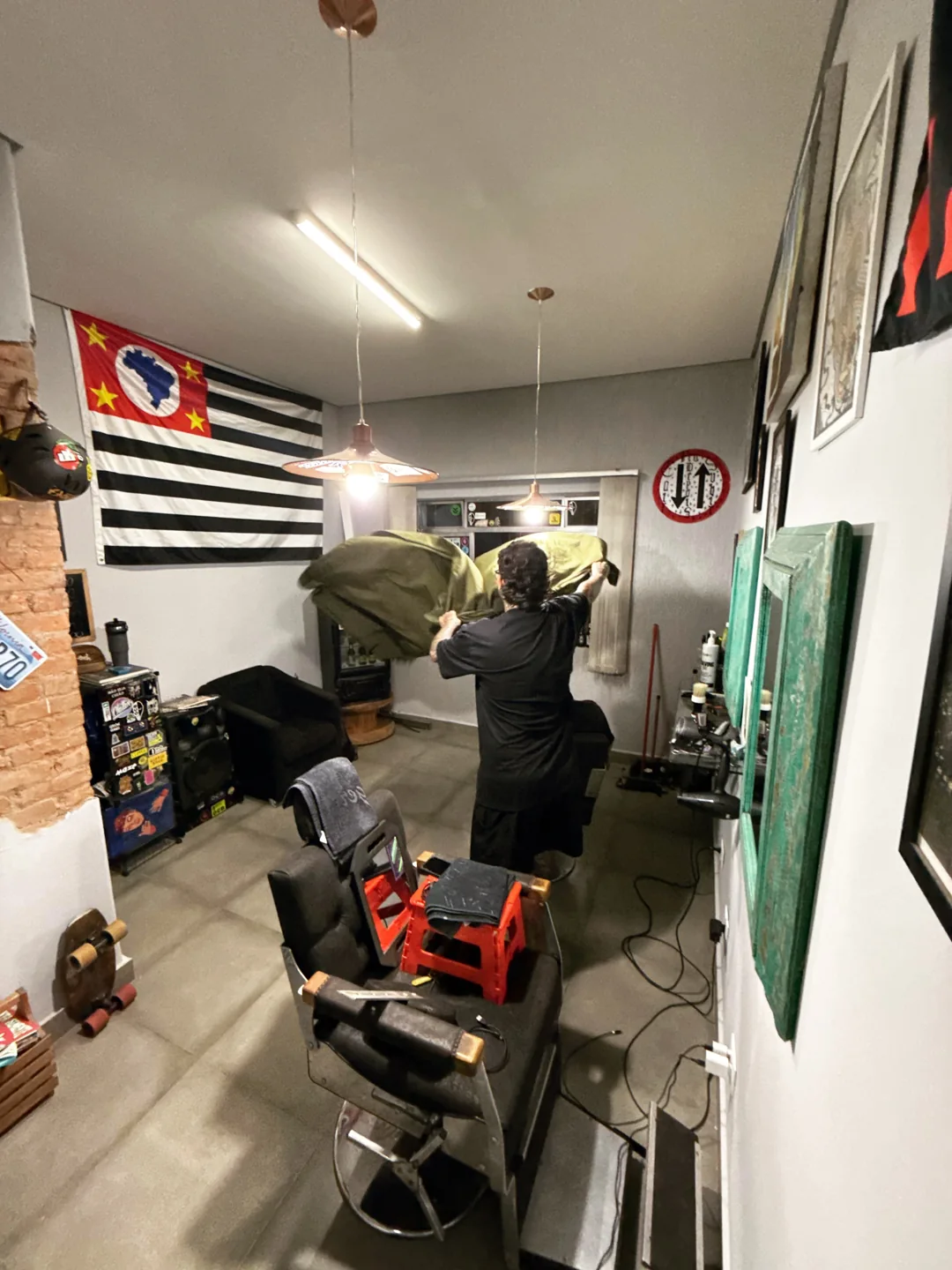 Interior da Peep Barber, com cadeiras de atendimento, espelhos e bandeira de São Paulo